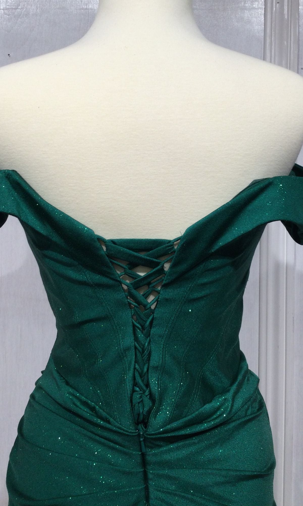 A mannequin wears the Ladivine CC2212 Lace-Up Long Glitter Prom Dress in emerald green, featuring an off-the-shoulder design and sparkling fabric—ideal as a plus size formal dress for special occasions.